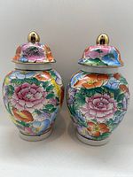 Front view of the two ginger jars showing floral hand-painted pattern with gold accents and lids with gold knobs.
