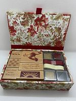 Open box showing multiple rubber stamps and ink pads inside decorative floral box