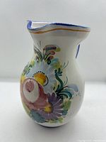 Front view of ceramic pitcher showing multicolour floral design with yellow, purple, pink, blue, and green flowers.