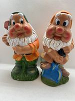 Front view of two hand painted garden gnomes standing side by side on white background.