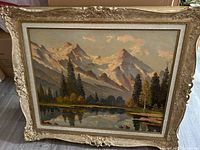 Frontal image showing the full painting including the ornate gold frame, displaying the mountain landscape scene with reflection on a lake.