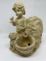 Photo of outdoor water fountain showing boy holding bird and dog beside basin with water nozzle