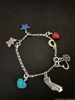 Full view of the silver charm bracelet showing all charms including California, hearts, star, butterfly, horseshoe, and shamrock.