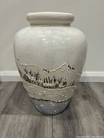 Front view of ceramic vase showing winter landscape with snow-covered houses and trees.