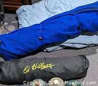 Two heavy blankets rolled and folded, one blue fleece and one gray quilted, with one Ed Dillan branded item visible