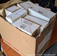 Opened cardboard box containing multiple boxed Christmas village houses and decorations.