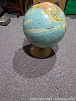 Full view of the globe showing the Americas and part of the Atlantic Ocean. The globe sits on a beige base on a carpeted floor.
