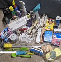 Photo showing cleaning products including sprays, Ajax cleanser, Lysol Cling, and power strips with utensil block and contact paper rolls.