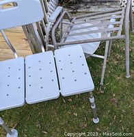 Photo shows a white plastic shower chair with perforated seat and adjustable legs. Next to it is a rusted metal commode frame with a white commode seat attachment.