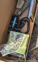Photo showing Weller soldering iron kit contents including power unit, soldering iron, metal coil stand, cleaning sponge, and accessory bag.