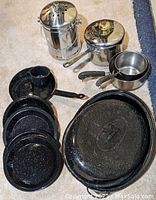 Photo showing 3 stainless steel pots with lids, 1 stainless steel composting garbage pale with roll of compost pale liners and charcoal filters, 1 large black roasting pan, 4 black metal plates, a frying pan and matching cup all made of black metal.