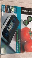 Front of Emerson electronic kitchen scale box showing the scale's display and two tomatoes as decoration.