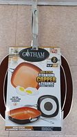 Photo of 12 inch Gotham Steel frying pan with packaging showing copper titanium ceramic non-stick surface and cooking instructions.