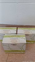 Three unopened boxes of Liquid Soap Products Luxury Bar Soap in coconut lime scent arranged on a floor against a wall.