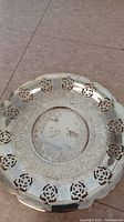 Top view of the medium round silver plate showing the floral cutouts and intricate engraved pattern at the center.