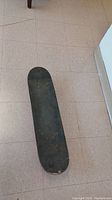 Top view of the skateboard showing worn black grip tape and general wear on the deck.