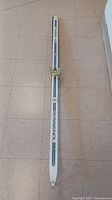 Top down view of one Rossignol ski showing white base color with blue and black stripes and the Rossignol brand name. Ski has attached binding.
