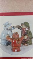 Front view of three ceramic snowmen figurines holding hands arranged in a circle around a candle holder.