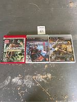 Photo of three PS3 game cases: Uncharted: Drake's Fortune Limited Edition, Uncharted 2: Among Thieves, and Uncharted 3: Drake's Deception, arranged side by side on a dark surface.