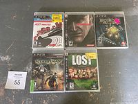 Top down photo showing five PS3 game cases laid out on a dark surface: Need for Speed Most Wanted, Metal Gear Solid 4, Bioshock 2, Starhawk, LOST Via Domus. Some have store price stickers.