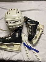 Koho helmet and pair of Bauer Supreme skates with skate guards laid on a white surface.