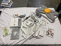 Full lot layout showing Nintendo Wii console, controllers, wheels, balance board, instruction manual, and two games (Wii Fit Plus and Mario Kart Wii).