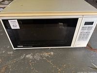 Side angled view of Home Line microwave oven showing door, control panel, and exterior condition.