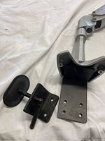 Close-up of bottom mounting bracket with missing screws and adjustable knob attached.