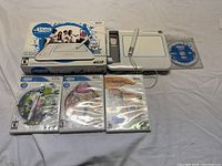 uDraw tablet in box with tablet out, three game cases, and uDraw Studio disc on table.