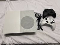 White Xbox One S console, black and white controllers, power cable