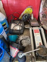 Hydraulic floor jack, battery charger, funnel, oil can, and a blue windshield fluid container visible