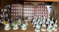 Shelf display of multiple collectible thimbles and several decorative bells featuring 3-D butterflies and birds.