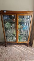 Full front view of the wooden display cabinet showing the leaded glass doors with metal decorative strips and the contents inside (not included).