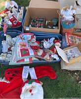 Wide view showing multiple bins and boxes filled with assorted Christmas decorations including stuffed animals, stockings, ornaments, and textiles.