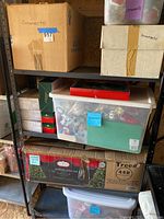 Boxes and bins labeled 'ornaments' on a black metal shelving unit inside a shed. The lot contents include multiple containers filled with Christmas ornaments.