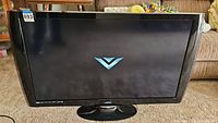 Front view of the Vizio flatscreen TV showing the Vizio logo on screen and the overall size and condition of the TV with its base.