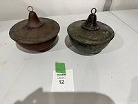 Two vintage copper lawn candles placed side by side on a white surface, showing overall shape, size, and patina for comparison.