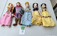 Overview of 5 Disney Princess soft dolls and Prince, laid out on white surface for condition and completeness check.