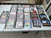 Photo of the full collection of classic rock CDs arranged in rows on a white table, visible album covers from various classic rock artists.