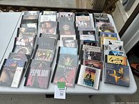 Photo showing a large selection of CDs arranged on a table including Loverboy, Pearl Jam, The Cult, and more.