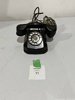 Front view showing rotary dial, handset resting on cradle, with visible numbering and central dial area.