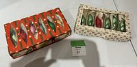 Photo showing two boxes of vintage Christmas bulbs side by side on a white surface, with a lot number card in front.