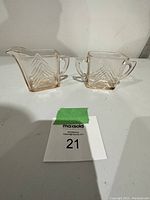 Pink depression glass creamer and sugar bowl displayed side by side, showing their shape and transparency.