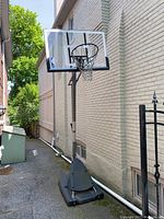 Front angled view of black portable base with pole and transparent backboard showing black metal rim and net.