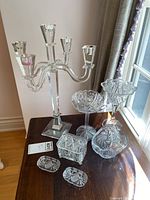Photo showing the 18 inch four-armed Shannon crystal candelabra along with two goblets, a pinwheel dish, rectangular covered crystal box, and two small oval dishes on a table by a window.