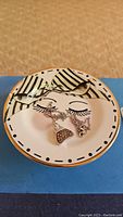Jewelry dish with zebra stripe and eyelash design holding the necklace