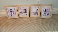 Four framed fashion prints representing London, Roma, Paris, New York leaning against wall