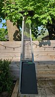 Full front view of propane patio heater against wooden fence under tree canopy