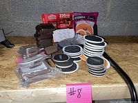 Various floor protectors including sliders, felt pads, and caster cups, arranged on a plywood surface.