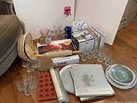 Photo showing multiple kitchen and baking items including glassware, bakeware, rolling pin, trivets, several vases, and cookbooks.